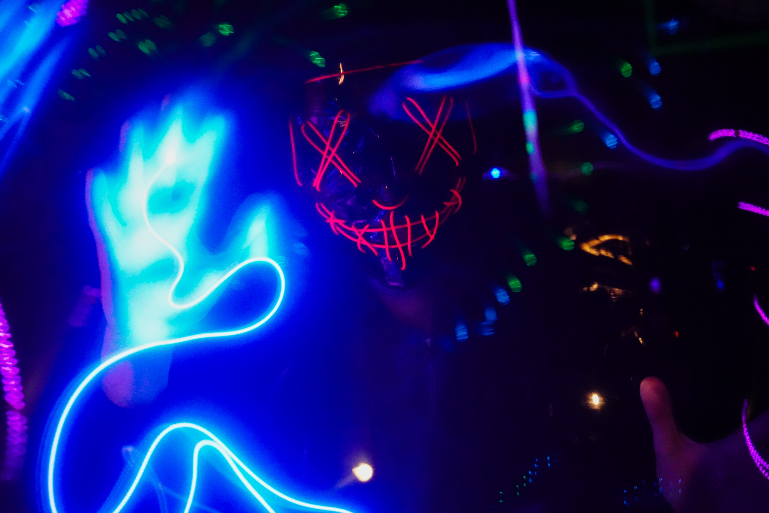 Visitante com máscara de Halloween interage com uma experiência do museu imersivo Neonia Porto.