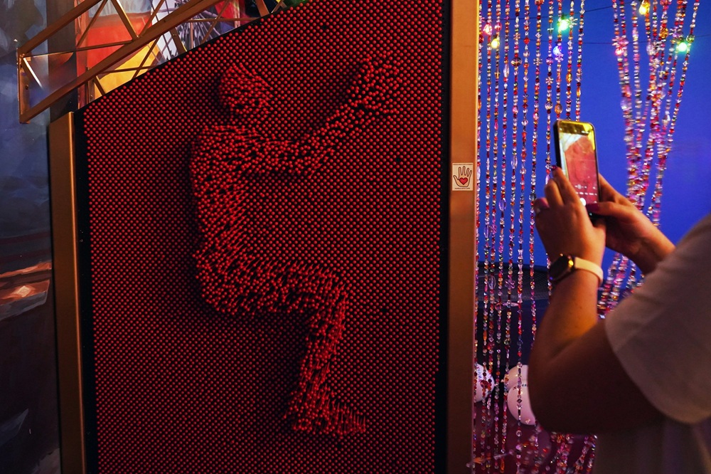 Human silhouette formed on a red pin wall in the interactive Arraial de São João room at Neonia Porto museum.