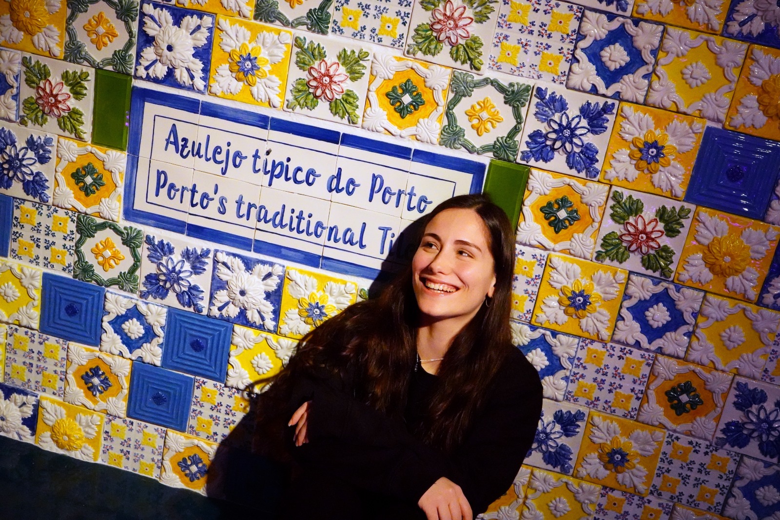 Visitante em frente a um painel de azulejos coloridos inspirado no azulejo tradicional do Porto, numa sala do museu Neonia Porto.