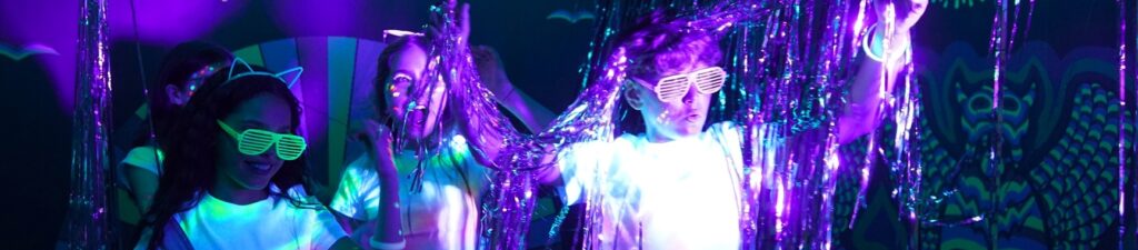 Crianças numa sala imersiva do museu Neonia Porto com iluminação UV, cores neon e elementos fluorescentes durante uma festa de aniversário.